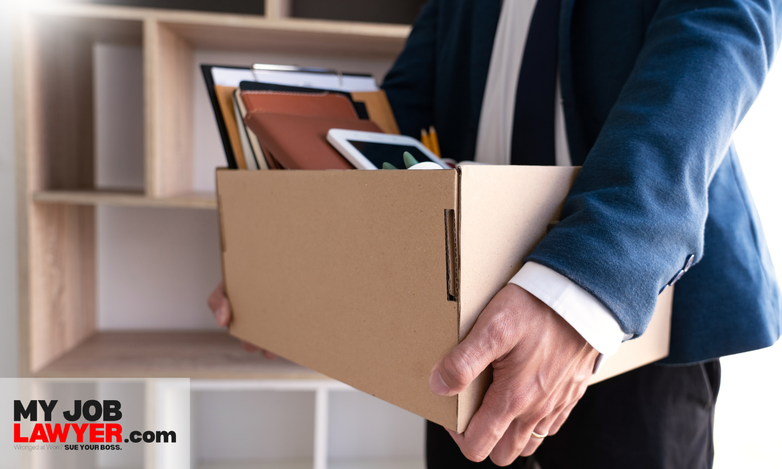 Older employee carrying a box of personal items while leaving the office, representing demotions and layoffs as age discrimination at work examples.